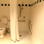 bathroom showing toilet and shower with seat